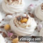 Εύκολες Πασχαλινές Φωλιές Μαρέγκας με Χρωματιστά Αυγουλάκια 7 Πασχαλινές φωλιές μαρέγκας σε μια λευκή πιατέλα.