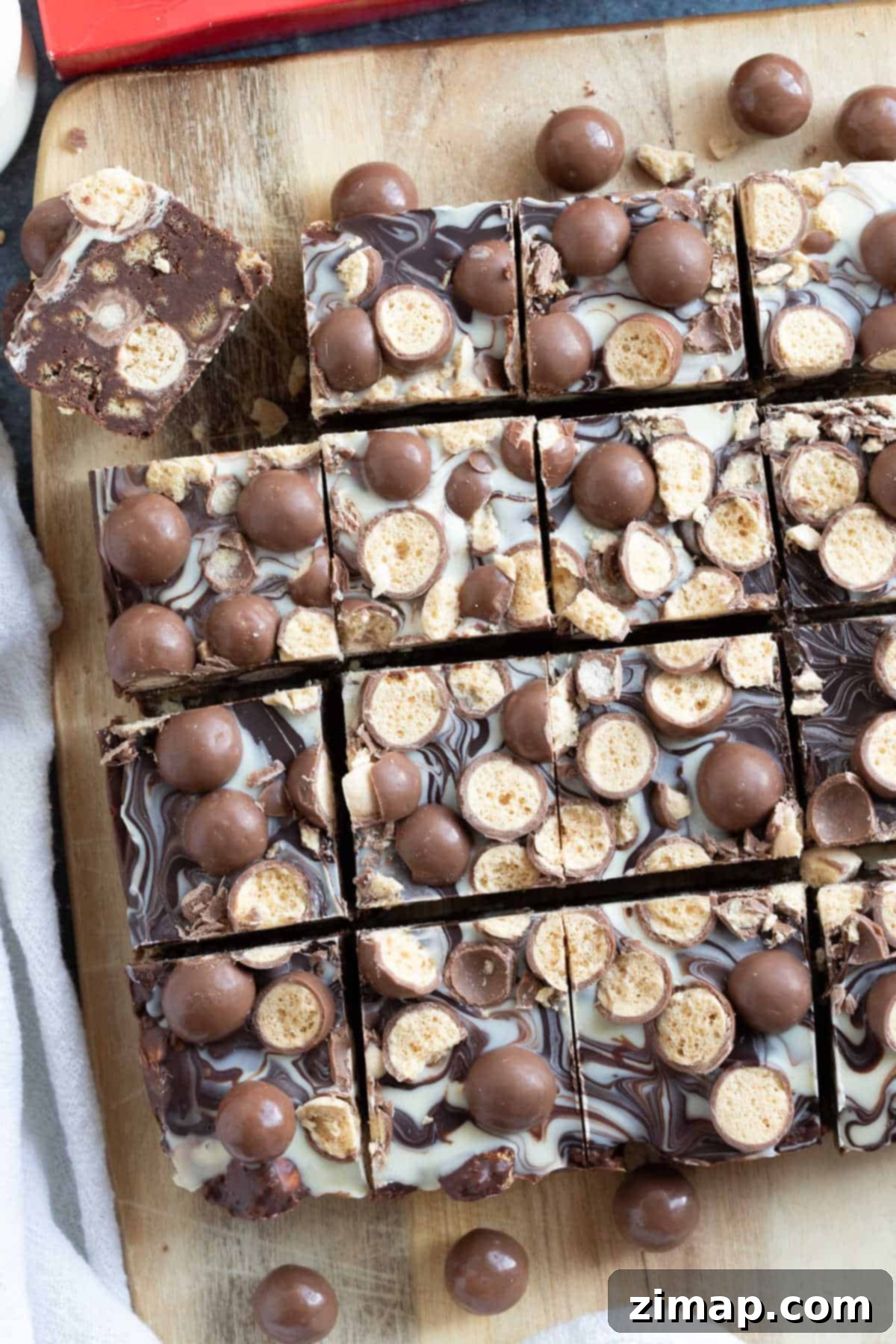Το Αξεπέραστο Μπισκοτογλυκό Μαλτέζερ 8 Overhead shot of Malteser tiffin on a wooden board, cut into bars.