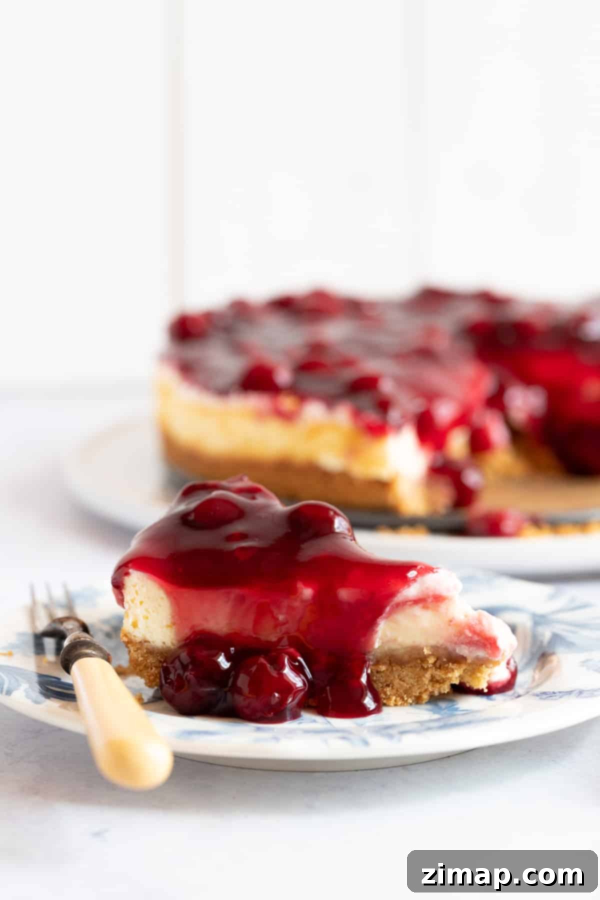 Εύκολο Τσίζκεϊκ με Κεράσια 2 Μια φέτα cheesecake βύσσινο σε πιάτο επιδόρπιου.