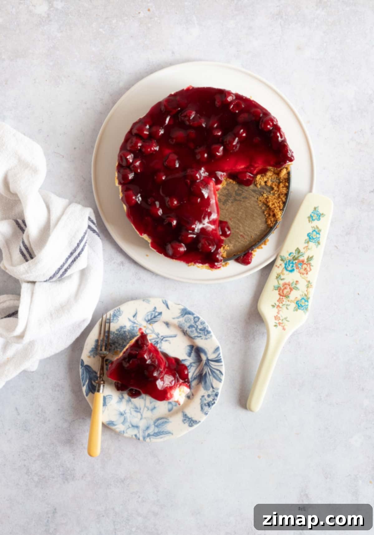 Εύκολο Τσίζκεϊκ με Κεράσια 4 Ένα cheesecake βύσσινο σε πιατέλα σερβιρίσματος, με μια φέτα να λείπει.