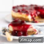 Εύκολο Τσίζκεϊκ με Κεράσια 7 Μια φέτα cheesecake βύσσινο σε ένα μπλε και λευκό πιάτο.