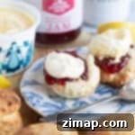 Εύκολα Σκονς Φριτέζας Αέρος 10 Σκόουνς από φριτέζα αέρος σε μπλε πιάτο με μαρμελάδα και πηχτή κρέμα.