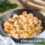 Εύκολη Συνταγή: Γαρίδες Πιλ Πιλ με Σκόρδο και Καυτερή Πιπεριά 8 Γαρίδες Pil pil σε μαύρο πιάτο.