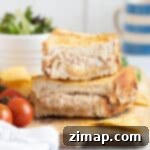 Η Απόλυτη Συνταγή Τόνου Melt για Φριτέζα Αέρος 13 Σάντουιτς tuna melt από air fryer σε ξύλινη σανίδα με σαλάτα και πατατάκια.
