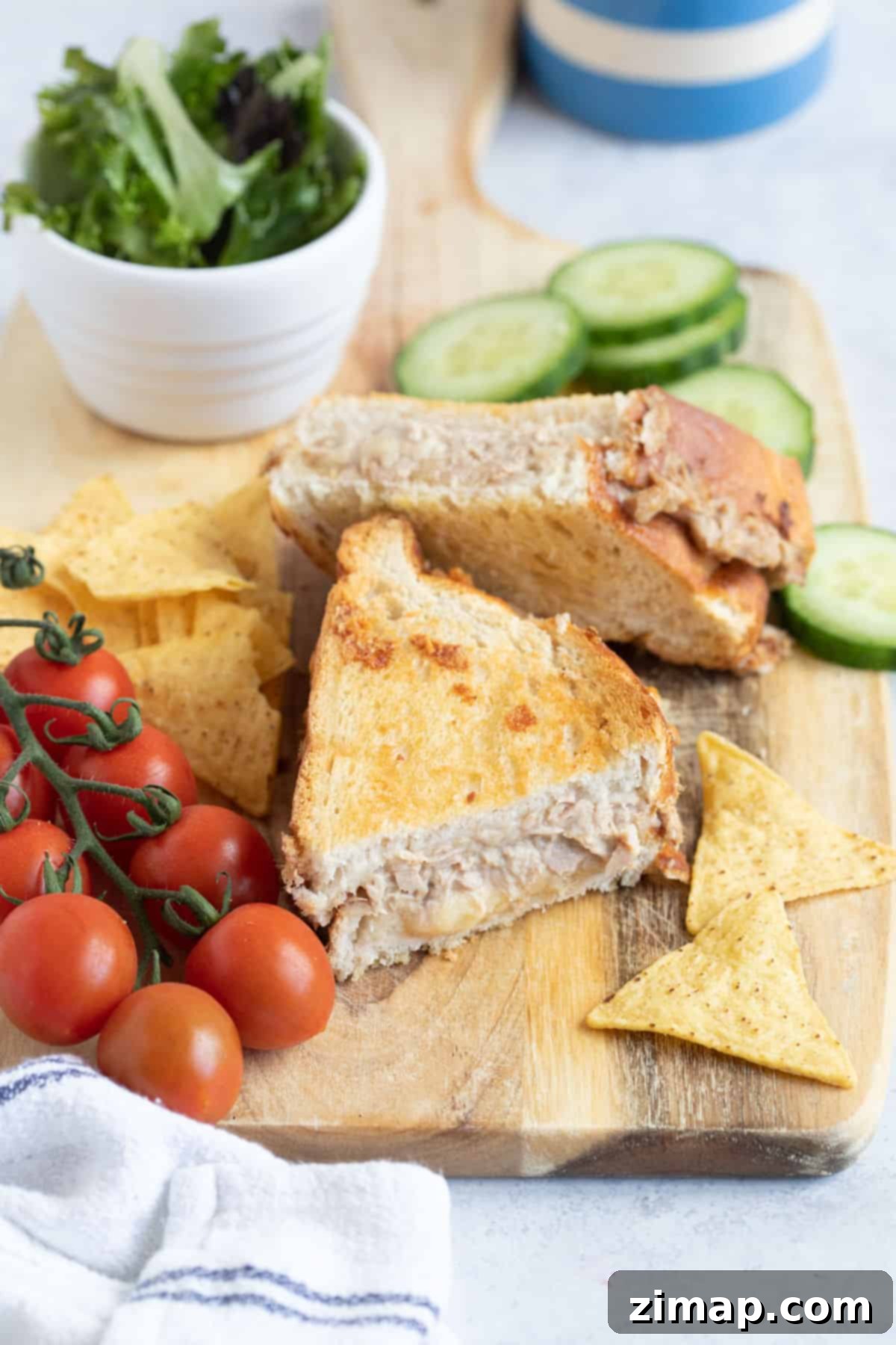 Η Απόλυτη Συνταγή Τόνου Melt για Φριτέζα Αέρος 10 Ένα tuna melt από air fryer σε ξύλινη σανίδα με λαχανικά σαλάτας.