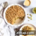 Κραμπλ Φραγκοστάφυλο χωρίς Κόπο 7 Crumble φραγκοστάφυλου σε στρογγυλό ταψί με κανάτα κρέμας ζαχαροπλαστικής.