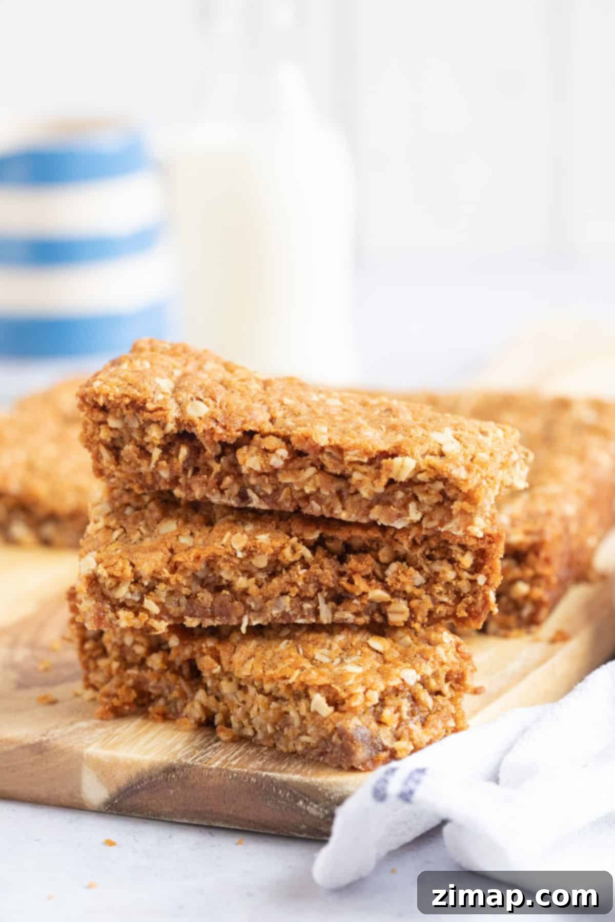 Εύκολη Συνταγή Anzac Slice 2 Μια στοίβα από φέτες Anzac σε ξύλινη επιφάνεια.