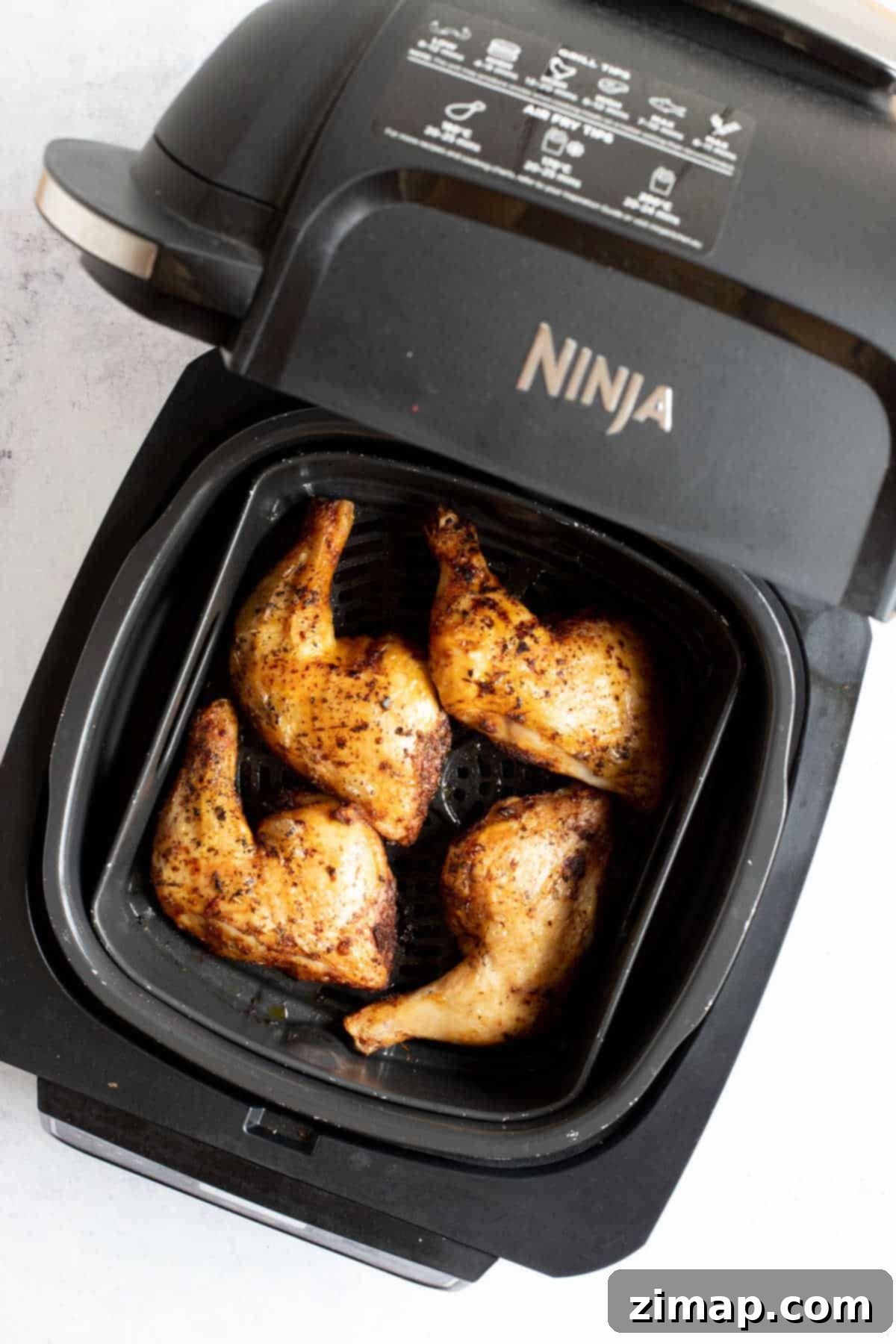 Αερόφρυτα Τραγανά Μπούτια Κοτόπουλου 2 Four chicken legs in a Ninja air fryer.