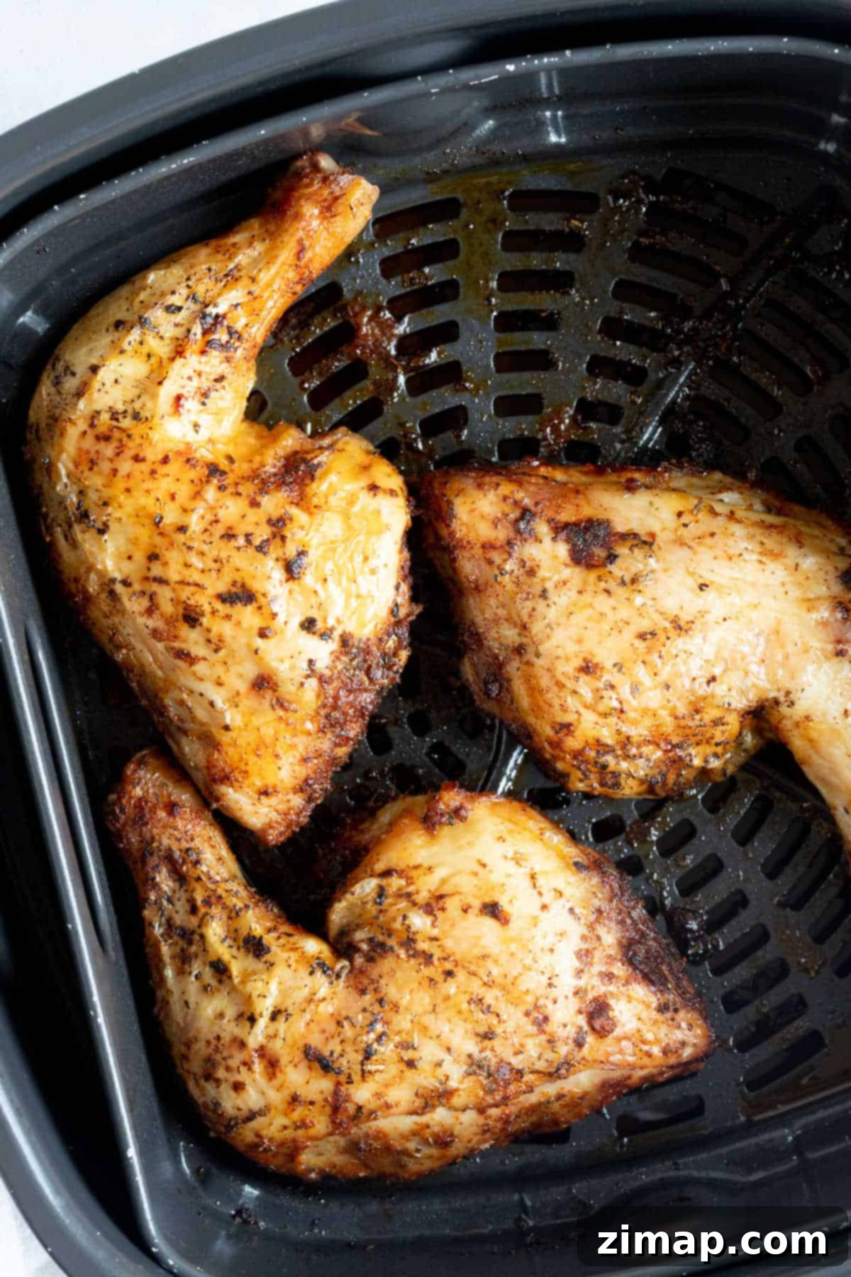Αερόφρυτα Τραγανά Μπούτια Κοτόπουλου 6 Crispy chicken legs in an air fryer basket.