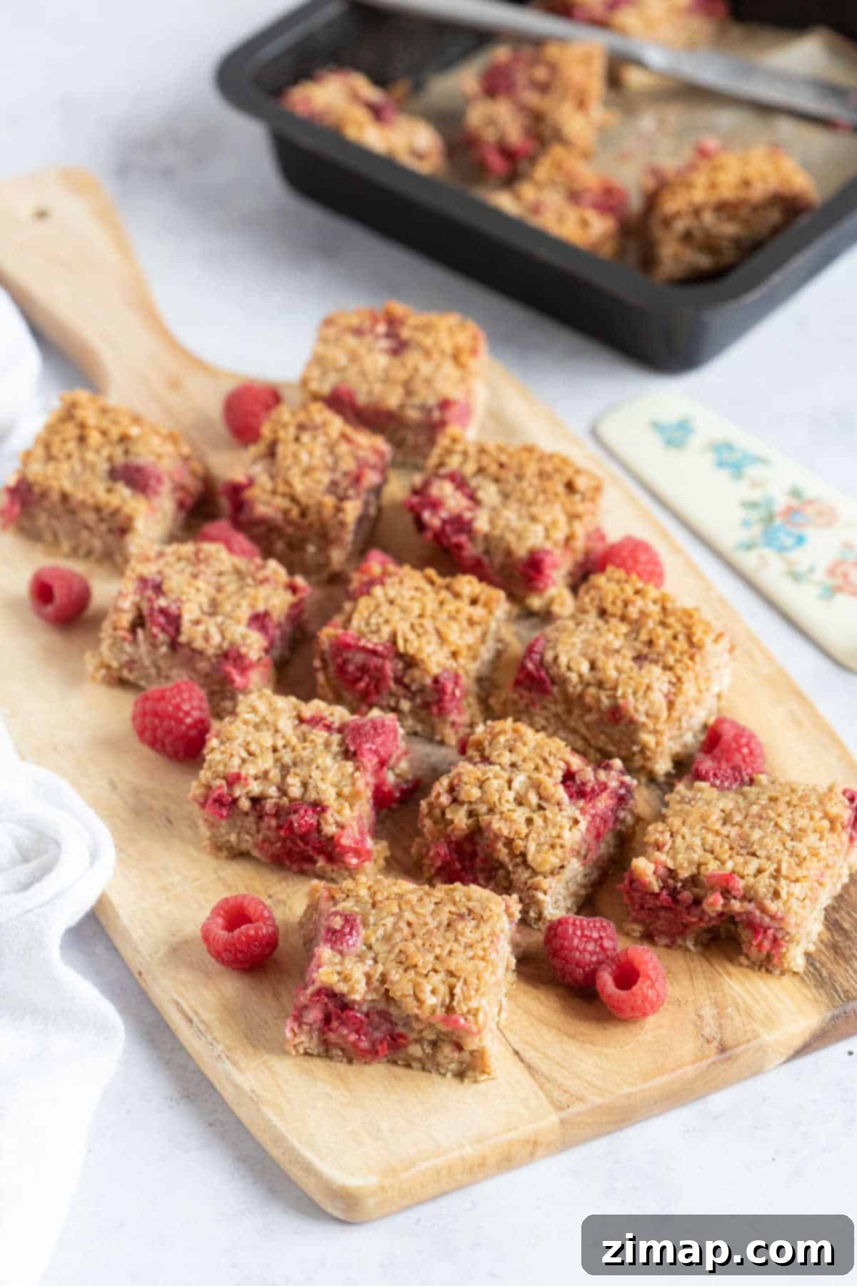 Οι Πιο Εύκολες Μπάρες Βρώμης με Σμέουρα 5 Raspberry flapjacks on a wooden board.
