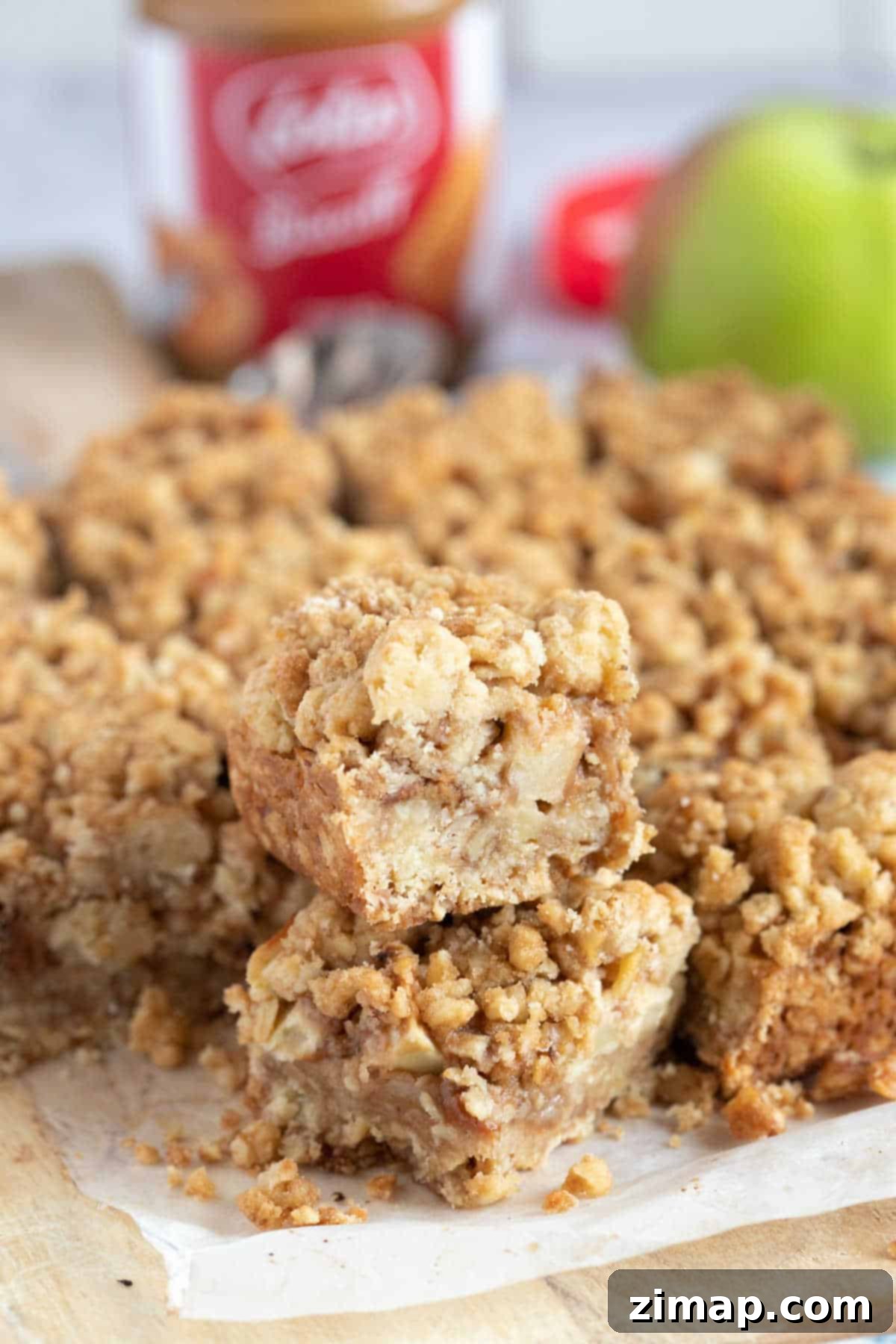 Μπάρες Μήλου και Biscoff Τριφτές 2 Μπάρες μήλου με Biscoff και τραγανή επικάλυψη σε ξύλινη επιφάνεια.