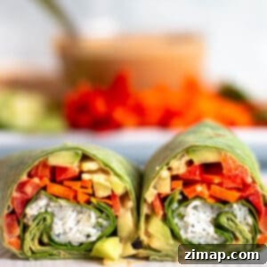 Ταϊλανδέζικα Τυλιχτά Κοτόπουλου 9 Ένα wrap σπανάκι γεμάτο με noodles, λαχανικά και σάλτσα φυστικοβούτυρο, με ένα μπολ σάλτσα φυστικοβούτυρο στο φόντο.
