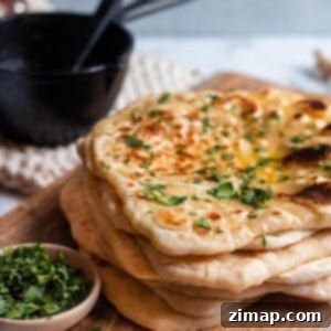 Προζυμένιο Νάαν με περίσσευμα 12 Στοίβα από sourdough naan σε ξύλινο δίσκο με κόλιανδρο και μαντεμένιο δοχείο για βούτυρο.