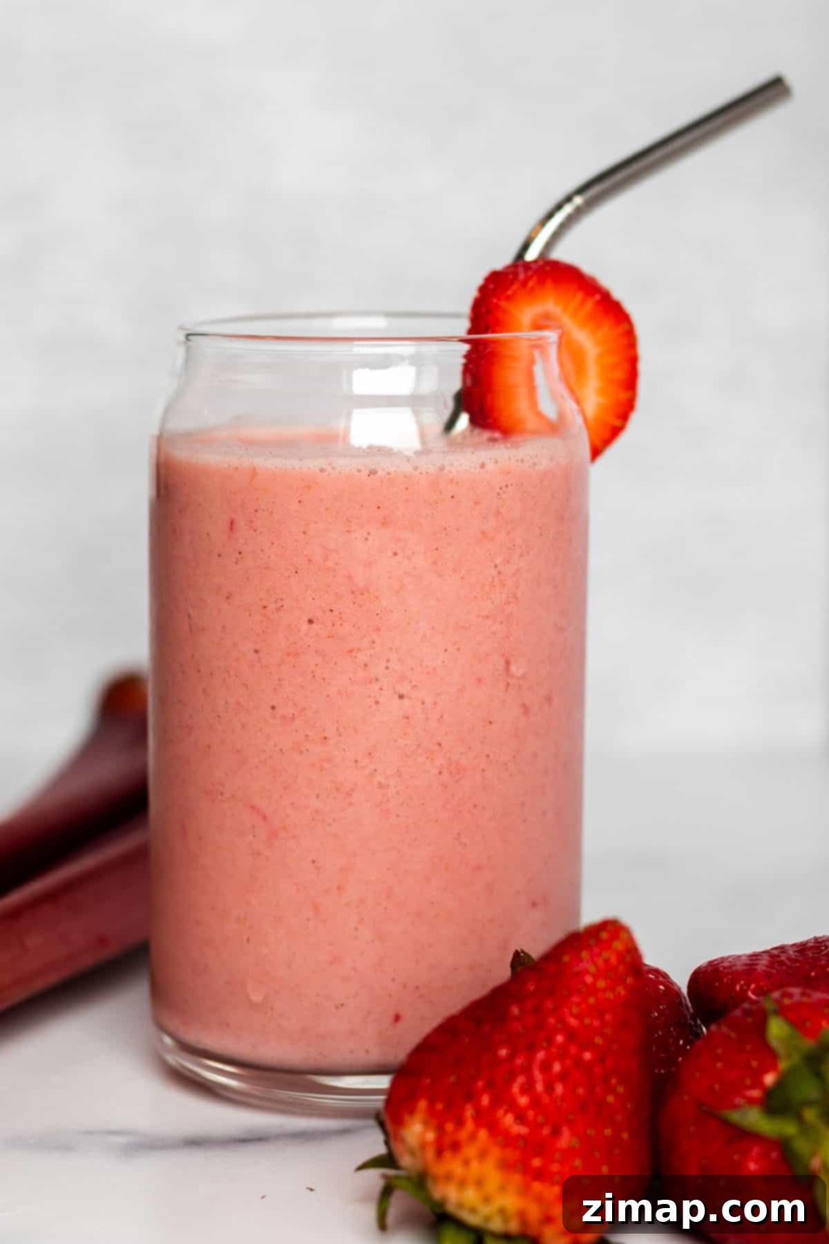 Σμούθι Φράουλας και Ραβέντι 2 Ένα ποτήρι με smoothie φράουλας-ραβεντιού, με στοίβες από φρέσκες φράουλες και κοτσάνια ραβεντιού.