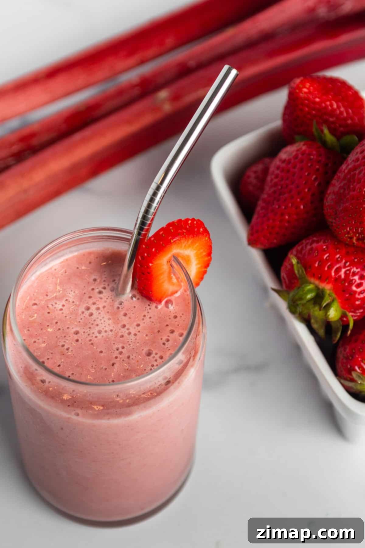 Σμούθι Φράουλας και Ραβέντι 6 Ένα ποτήρι με smoothie, μια φέτα φρέσκια φράουλα και φρέσκο ραβέντι και φράουλες.