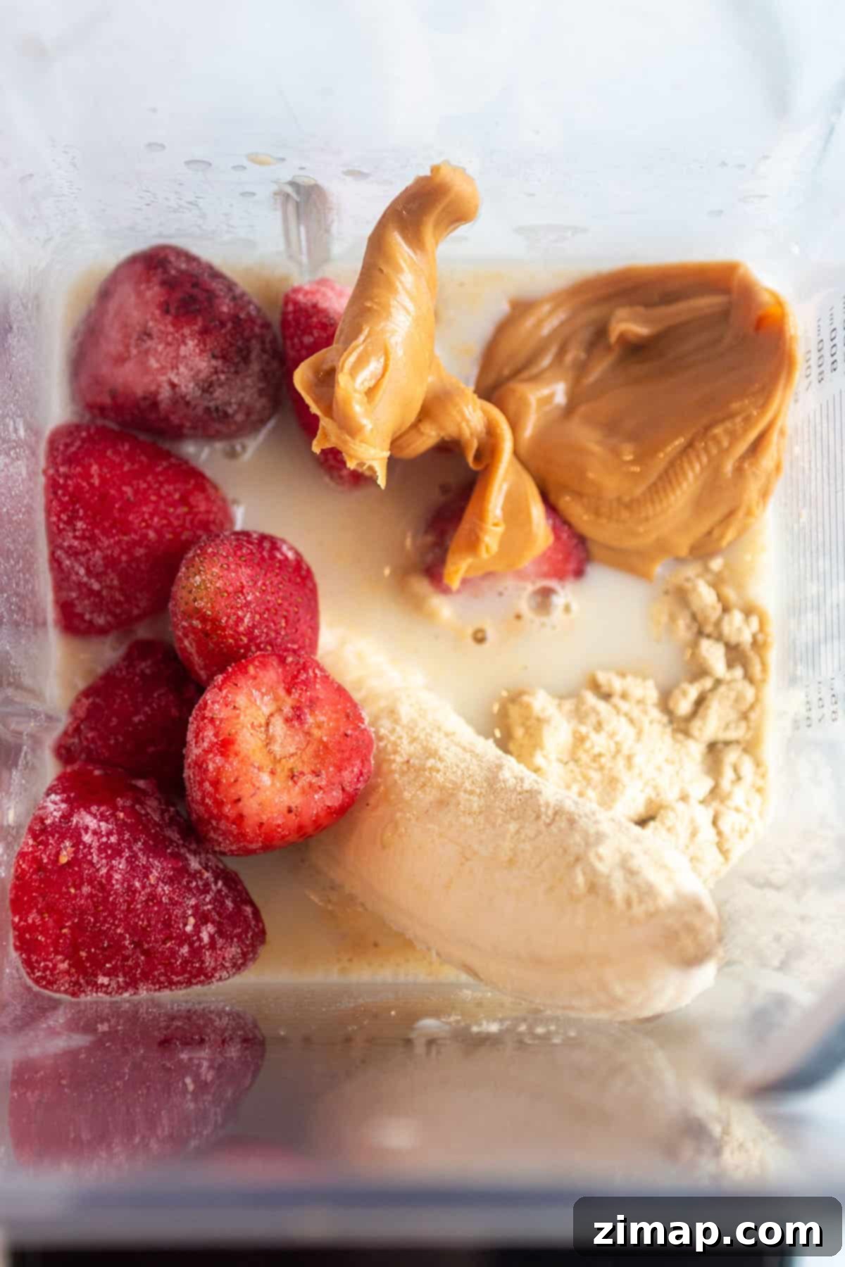 Πώς να φτιάξεις smoothie μπανάνας χωρίς γιαούρτι 4 Ένα βάζο μπλέντερ με γάλα βρώμης, ολόκληρη μπανάνα, κατεψυγμένες φράουλες, φυστικοβούτυρο και σκόνη πρωτεΐνης.