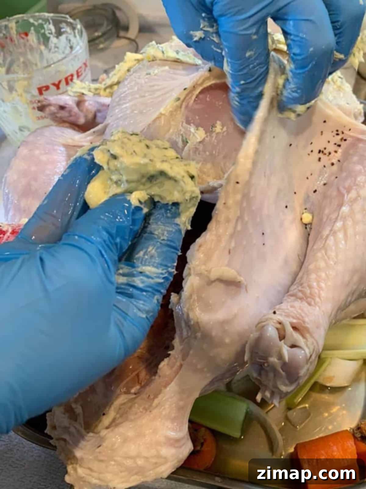 Η Τέλεια Καπνιστή Γαλοπούλα με Ψησταριά Πέλλετ 7 Δύο χέρια που γεμίζουν μια ένωση βουτύρου κάτω από την πέτσα μιας γαλοπούλας.