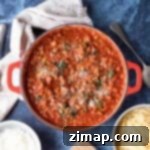 Εύκολη Μπολονέζ Κουόρν 6 Quorn bolognese σε κόκκινη κατσαρόλα με τριμμένη παρμεζάνα.