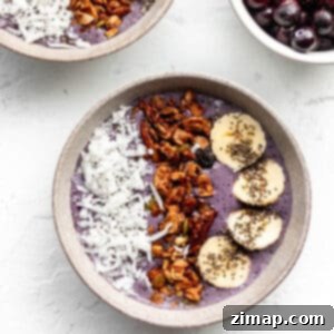 Μύρτιλο Σμούθι Μπολ 5 Ένα μπολ με ένα μωβ smoothie με επικάλυψη καρύδας, granola και φέτες μπανάνας.