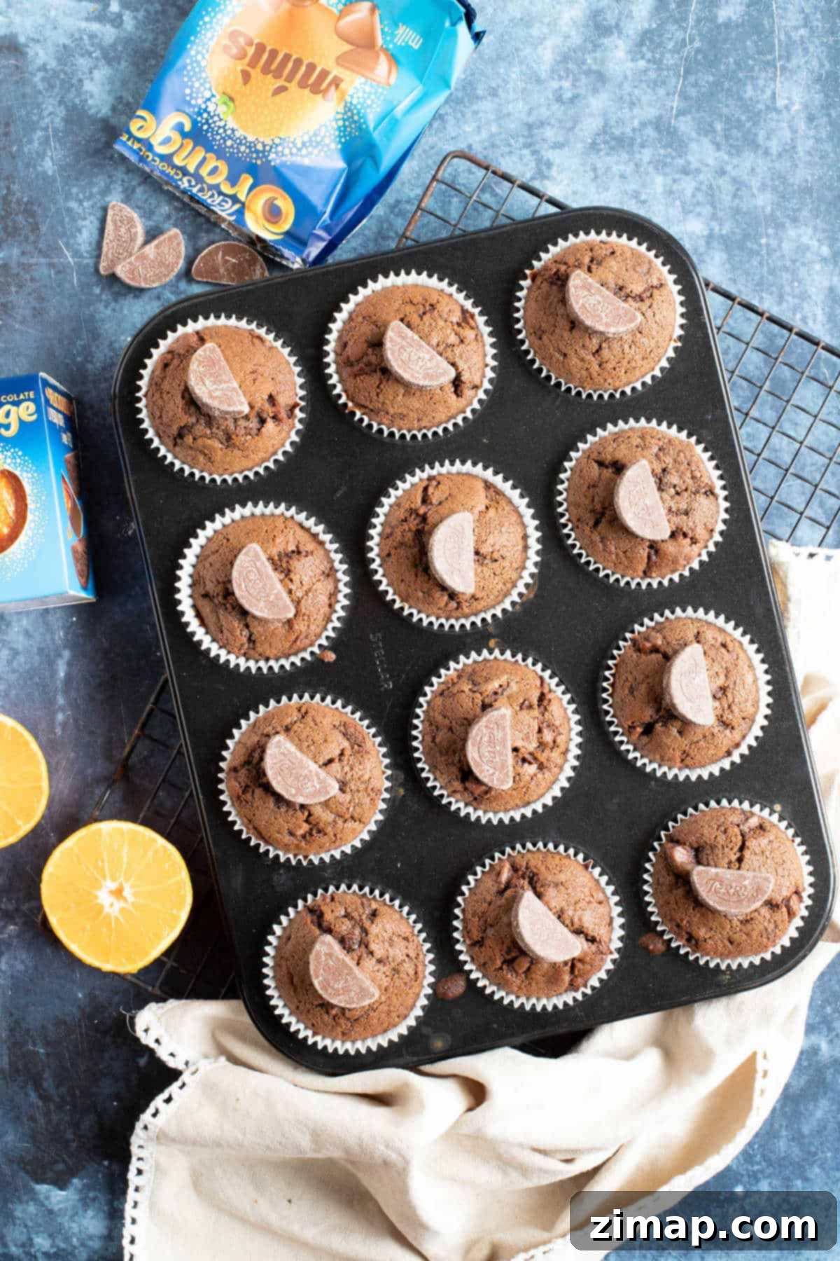 Εύκολα Μάφινς Σοκολατοπορτοκαλένια 2 Chocolate orange muffins in a baking tin.