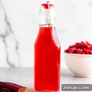 Σιρόπι Ραβέντι 9 Ένα γυάλινο μπουκάλι με αναδιπλούμενο καπάκι με ένα απλό σιρόπι ραβέντι και φρέσκο ραβέντι.
